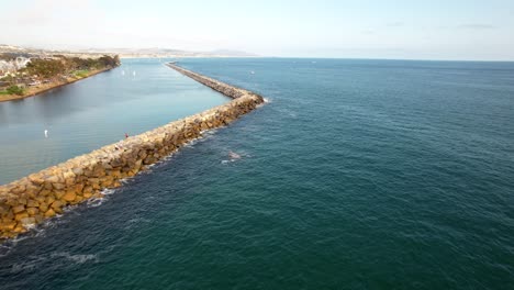 The-stone-jetty-at-Dana-Point,-California-harbor-protects-the-marina-and-shoreline-from-erosion---aerial-flyover
