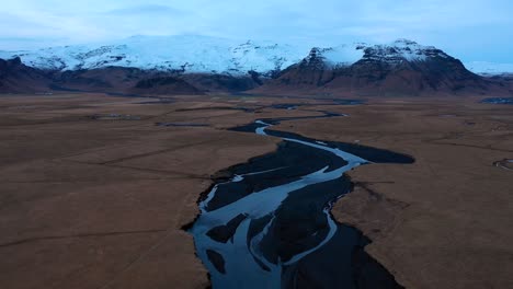 Drone-flyover-at-dusk-in-southern-Iceland-with-river-and-Eyjafjallajökull-in-the-background