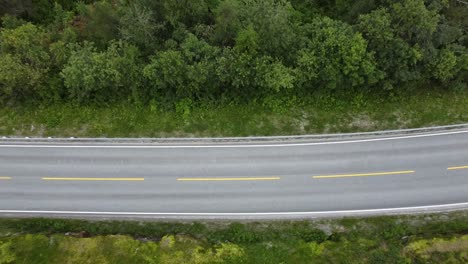 Top-down-view-over-a-white-car-passing-by-a-lake-in-Norway