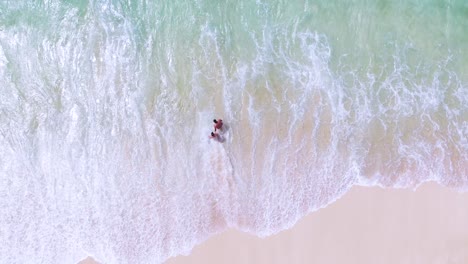 Aerial-view-of-tourists-on-the-beach,-swimming-in-waves,-vacation-concept