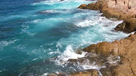 Beach-paradise-Cabo-Mexico-ocean-beach-pans-up-from-rocks-to-reveal-ships-on-the-horizon