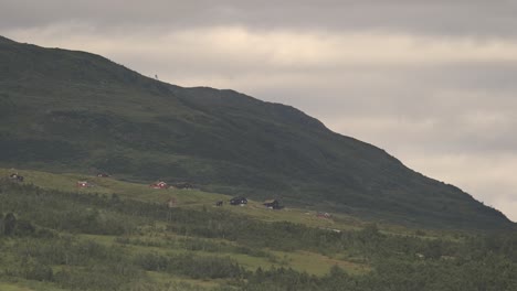 Abendlicher-Zeitraffer-Von-Revhaugen-In-Myrkdalen-Norwegen---Wolken-Und-Sonnenlicht-Ziehen-Schnell-über-Grüne-Idyllische-Berglandschaft-Mit-Ferienhäusern---Warmes-Licht-Am-Abend-Vor-Sonnenuntergang