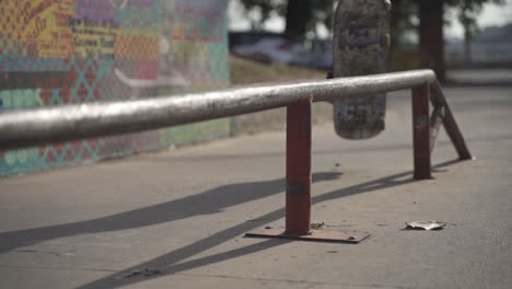 Slow-motion-close-up-of-skater-skateboarding-and-grinding-on-rail-outdoors-at-skate-park-during-sunny-day