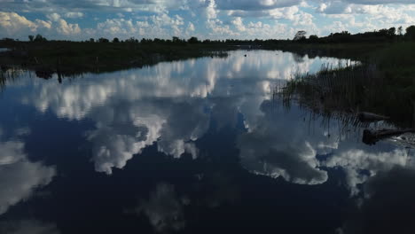 Static-wide-establishing-shot-of-cumulous-clouds-mirrored-on-a-pond-surface