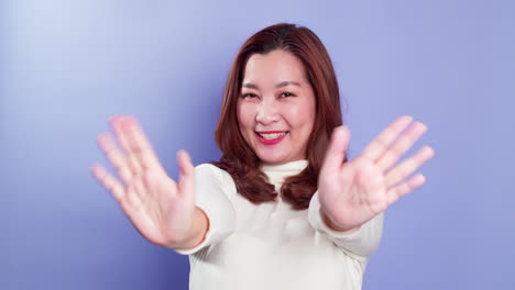 Porträt-Einer-Asiatischen-Glücklichen-Frau-Winkt-Der-Kamera-Zu-Und-Macht-Hallo-Gesten,-Während-Sie-Isoliert-über-Einem-Violetten-Hintergrund-Steht-2