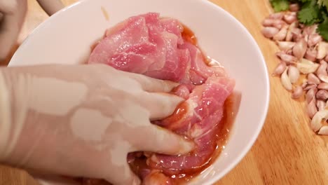 Hand-with-Glove-Mix-Pork-Loin-with-Marinated-Sauce-in-White-Bowl,-Close-Up