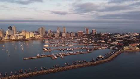 Spectacular-cinematic-footage-of-Punta-del-Este-city-skyline-in-Uruguay-at-sunset-with-port-and-docked-yachts
