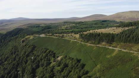 Aerial-view-of-an-empty-long,-winding-mountain-road-in-the-Wicklow-Mountains-on-a-sunny-day
