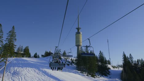 Main-chairlift-at-Oslo-vinterpark-with-skiers,-Tryvann-tower,-Winter-Park-ski-resort