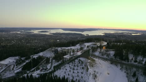 Oslo-city-drone-push-in,-Vinterpark-Winterpark-Tryvann-Past-Ski-Jump-at-Sunset-Holmenkollen-with-nordic-cross-country-skiing