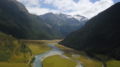 Aerial-view-peeking-around-the-corner-of-a-huge-valley-in-New-Zealand-towards-a-distant-glacier