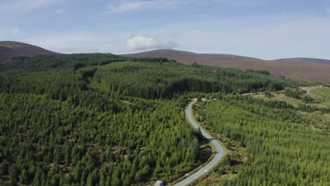 Aerial-view-of-an-empty-winding-mountain-road-in-the-Wicklow-Mountains-on-a-sunny-day