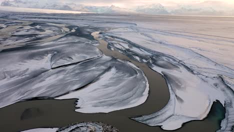 Drone-flight-over-landscape-with-first-snow,-over-glacial-river-near-Skaftafell-in-Southern-Iceland