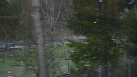 School-Soccer-fields-seen-from-train-to-Oslo-Vinterpark,-Grakammen,-Sentrum-city-centre