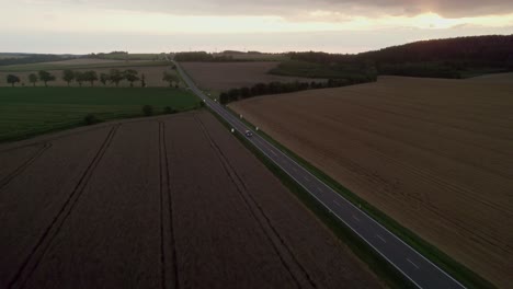 Aerial-view-of-cars-passing-on-rural-asphalt-road-with-a-beautiful-landscape