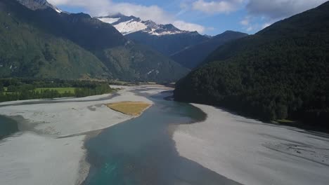 Aufsteigender-Schuss-Eines-Eisigen-Flusses,-Der-An-Einem-Sonnigen-Tag-Auftaut,-Mit-Einem-Eisbedeckten-Gletscher-In-Der-Ferne