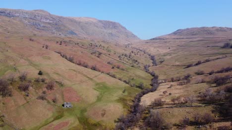 Reverse-Drone-View-Of-Kirkstone-Pass-Area-Valley-Floor-Looking-Up-To-Red-Screes-Fell-With-Old-Farm-Building-And-Autumn-Colours