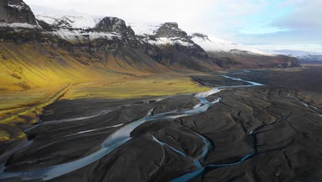 Slow-drone-flight-with-autumn-snowcapped-mountains,-Icelandic-braided-river,-black-sand-in-Southern-Iceland,-Vatnajokull-area