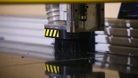 A-CNC-router-head-moves-with-precision,-cutting-black-signage-in-slow-motion-with-debris-flying-off