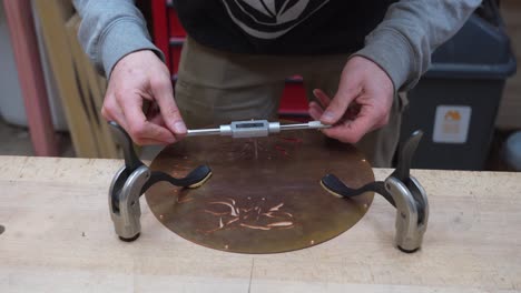 Guitar-Build---Craftsman's-Hands-Tapping-a-Hole-in-Copper-Guitar's-Cover-Plate-at-the-Work-Bench