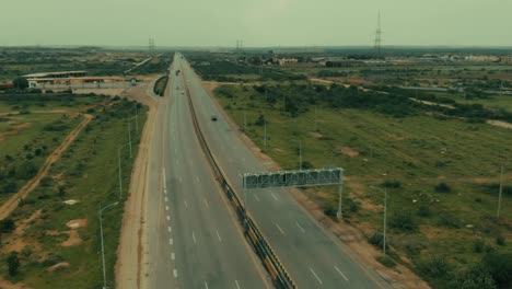 Antenne,-Die-über-Die-Karachi-Autobahn-Mit-Pylonen-Im-Hintergrund-Zurückfliegt