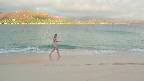 Young-blond-girl-in-swimsuit-walks-on-a-beach-in-Kailua,-Hawaii,-slow-motion