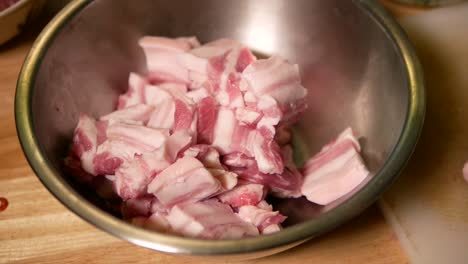 Adding-Raw-Pork-Belly-into-Metal-Mixing-Bowl,-Close-Up-1
