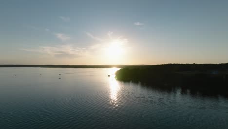 Aerial-drone-shot-of-boats-on-a-large-lake-at-sunset