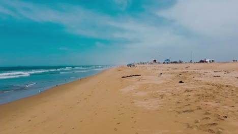 Drone-flies-along-beach-as-waves-wash-in-shore