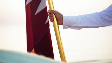 Un-Caballero-Que-Sostiene-La-Bandera-De-Qatar-Cerca-Del-Mar