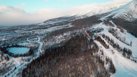 High-Tatras-ski-jump-tower,-snowy-white-mountain-landscape,-aerial-drone-view,-day