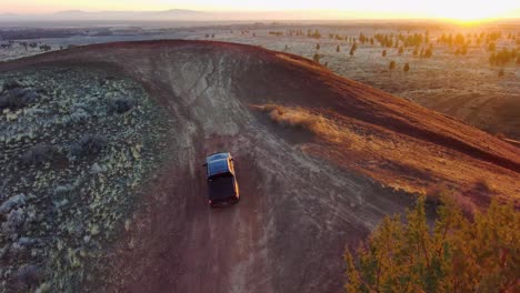 Rotating-from-above,-truck-drives-up-a-remote-off-road-hill-at-sunrise-4k-60fps