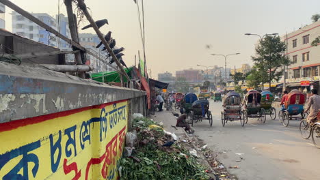 Dhaka-street-traffic-and-piles-of-garbages-on-side,-handheld-view