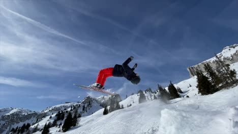 A-young-ski-freestyle-athlete-is-performing-a-backflip-with-skis-on-a-swiss-alps-snow-slope-with-a-fir-forest-in-the-winter