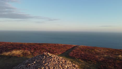 Aerial-Drone-of-Stone-Cairn-and-Sea-with-Wales-in-Distance-at-Holdstone-Down-Exmoor-Devon-UK-4K