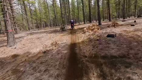 Race-drone-close-up-following-male-motorcycle-rider-through-trees,-60fps
