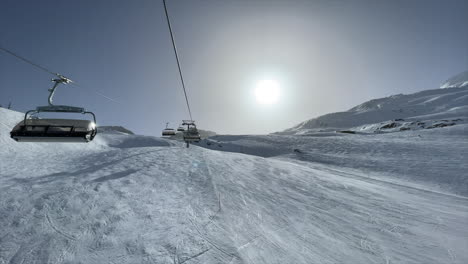 Chairlift-in-the-swiss-alps-over-ski-slopes-during-winter,-Zermatt,-sunny-sky