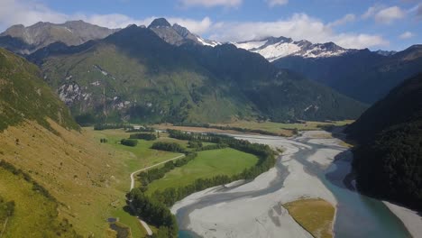 Schwenk-über-Ein-Riesiges-Tal-Mit-Einem-Zugefrorenen-Fluss-Zu-Einem-Dunklen-Wald-An-Der-Seite-Eines-Berges-In-Der-Alpinen-Region-Neuseelands