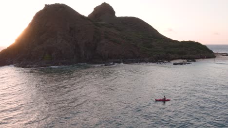 Man-kayaking-in-front-of-Na-Mokulua-twin-islands-in-Hawaii,-establishing-aerial-view