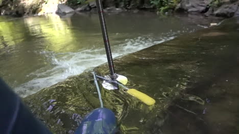 A-scientist-with-boots-tries-to-measure-the-flow-of-a-river-with-a-magnetic-probe-and-a-meter