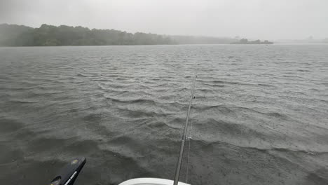 POV:-a-man-is-fishing-on-a-boat-in-the-middle-of-a-Lake-and-a-storm,-heavy-rain-falls-on-the-water