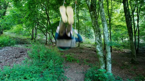 Young-adult-swinging-on-giant-swing-in-forest-with-blue-hair-en-yellow-shoes