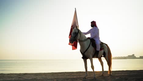 Ein-Ritter-Zu-Pferd,-Der-Die-Katar-flagge-Nahe-Dem-Meer-Hält-5