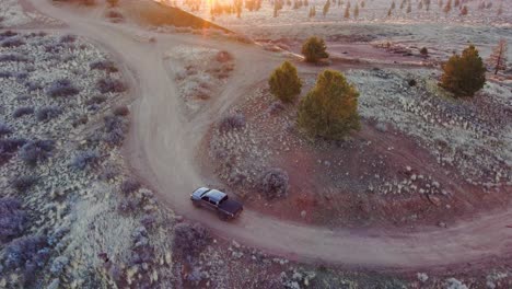 Close-up-to-wide-shot-of-a-truck-driving-up-a-remote-off-road-hill,-sunrise,-4k-60fps
