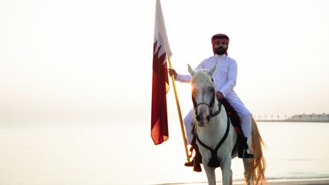 Ein-Ritter-Zu-Pferd,-Der-Die-Katar-flagge-Nahe-Dem-Meer-Hält-3