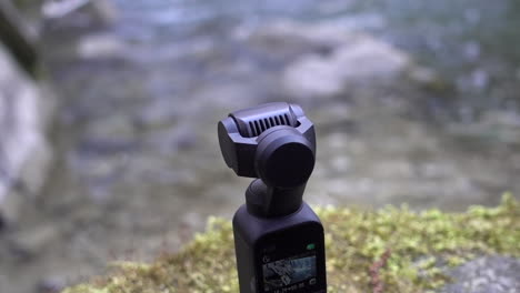 Eine-Dji-Osmo-Pocket-Camera-Steht-Auf-Einer-Moosunterlage-Am-Rand-Eines-Flusses-In-Den-Schweizer-Alpen
