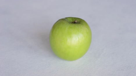 Hand-Puts-Fresh-Green-Apple-On-The-Table