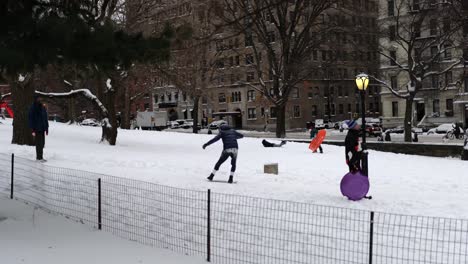Adults-and-children-sledding-snowboarding-slow-motion-in-Central-Park,-New-York-City