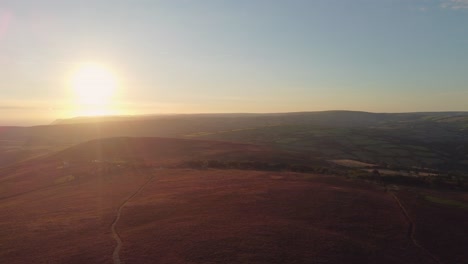 Beautiful-Sunrise-Aerial-Drone-of-Moorland-with-Purple-Heather-Early-Morning-Sun-Flare-and-Fog-in-Distance-4K