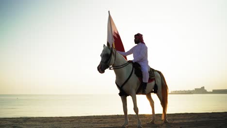 Ein-Ritter-Zu-Pferd,-Der-Die-Katar-flagge-Nahe-Dem-Meer-Hält-2